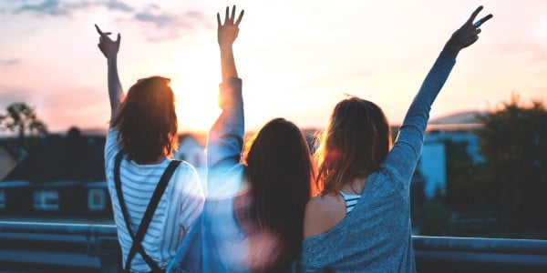 benefits of time management - back of friends with hands in the air, excited, having fun