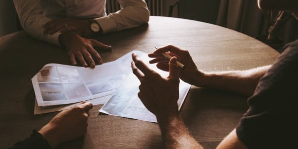benefits of time management - people meeting around a round table, just see hands and paper and table