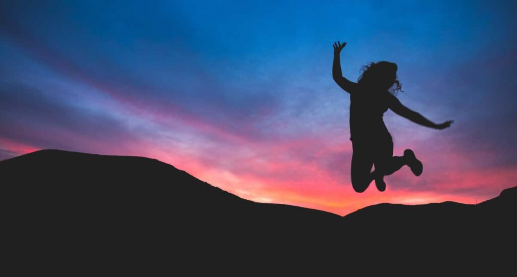 benefits of time management - woman jumping in sunset