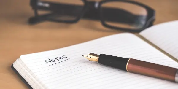 time management skills - notebook that says "notes" on it with pen on notebook